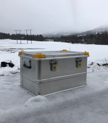 Viking Aluminiumkiste in einer verschneiten Landschaft, mit sichtbaren Metallverschlüssen und gelben Eckenschutzvorrichtungen.