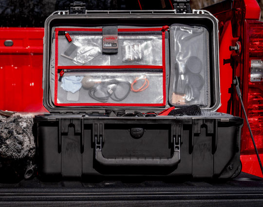Geöffneter harter SKB-Koffer mit Deckelorganizer mit transparenten Reißverschlusstaschen, gefüllt mit Kleinteilen und Zubehör, im Fond eines Fahrzeugs platziert.
