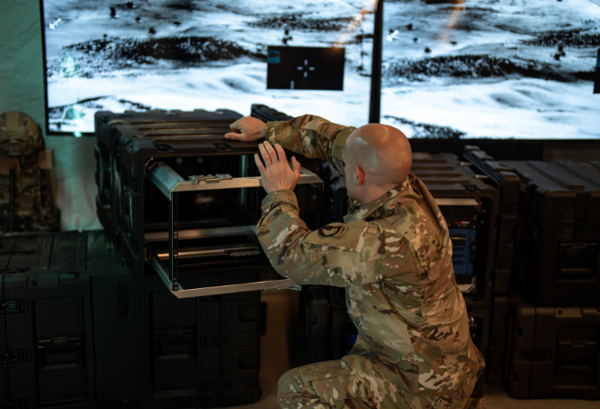 Militärangehöriger arbeitet an einem offenen 19-Zoll-SKB-Rack, umgeben von mehreren geschlossenen 19-Zoll-SKB-Racks in einer Betriebsumgebung.