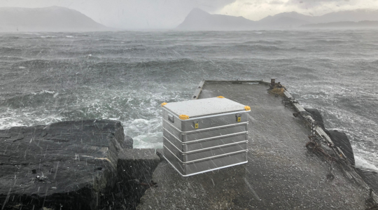 Spritzwassergeschützter Viking-Aluminiumkoffer, der bei starkem Regen und rauen Wetterbedingungen auf einem Pier am Meer aufgestellt wurde.